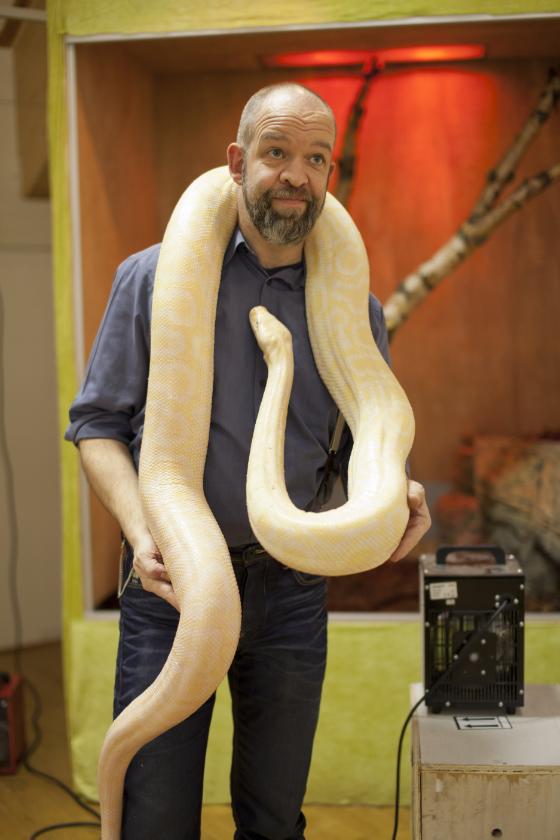 Per Helge Nylund ved Tromsø Museum poserer her med en av slangene i utstillingen.