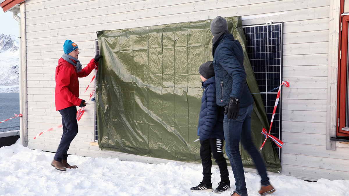Direkt&oslash;r i NVE, Kjetil Lund og en elev fra Hus&oslash;y skole avdekker solcellepaneler som skal forsyne skolen med energi. Avdukingen markerte &aring;pningen av prosjektet Smart Senja. 