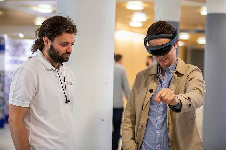En mann ser på en annen mann med VR-briller på hodet.