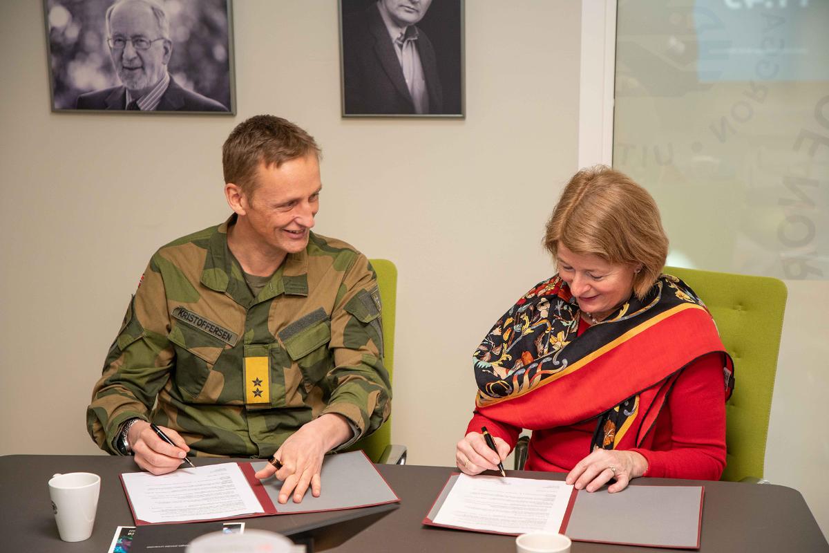 Mann i uniform signerer kontrakt med rektor Anne Husebekk