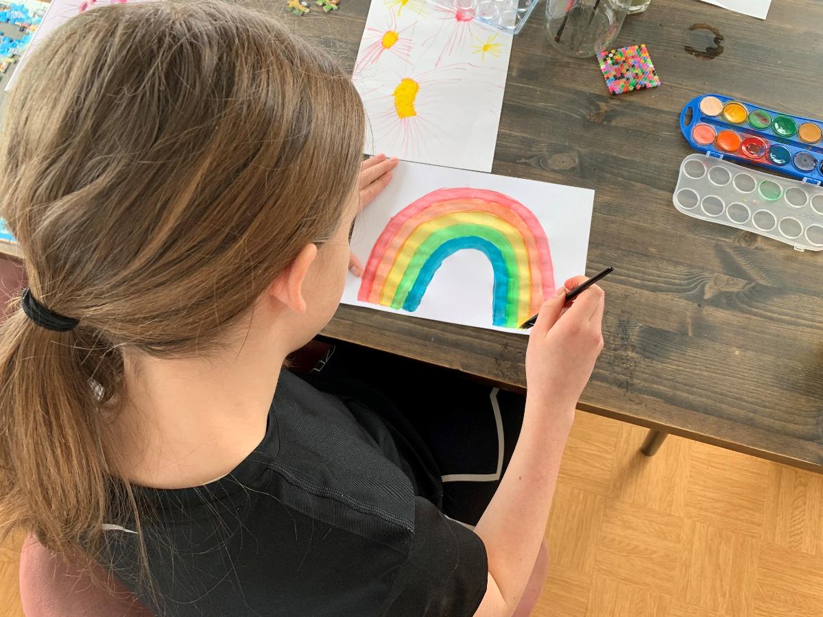 jente som maler regnbue i forbindelse med koronanedstenging