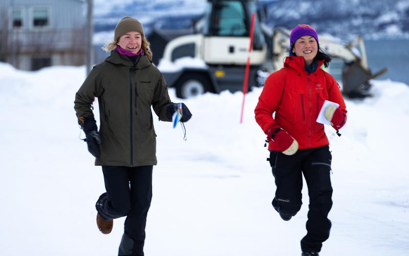 To unge kvinner løper smilende.