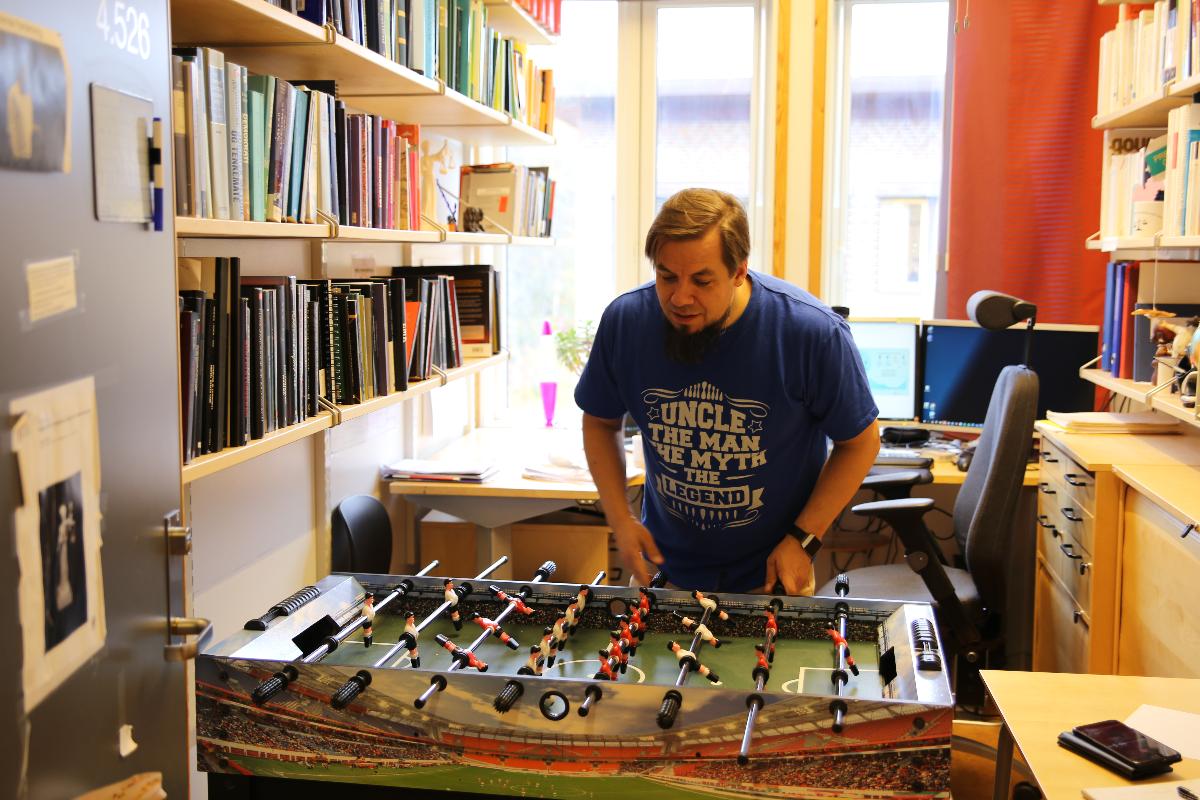 Marius Storvik viser frem foosballbordet han har på kontoret sitt, det har ingen tilknytning til utstillingen hans på Tromsø Museum.