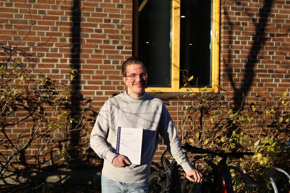Sverre M. B. Salvesen viser frem boka "Kreditorvern" ved sykkelparkeringen på UiT. 