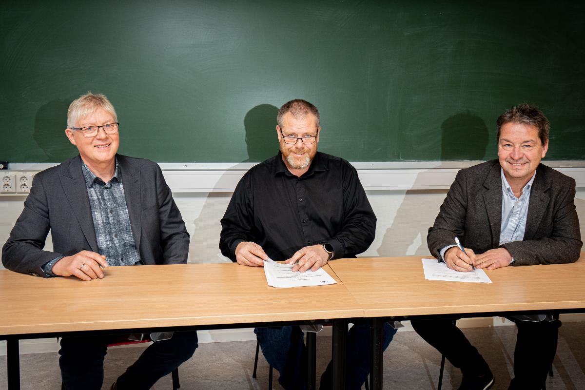 Bildet av tre representanter som signerer avtale.