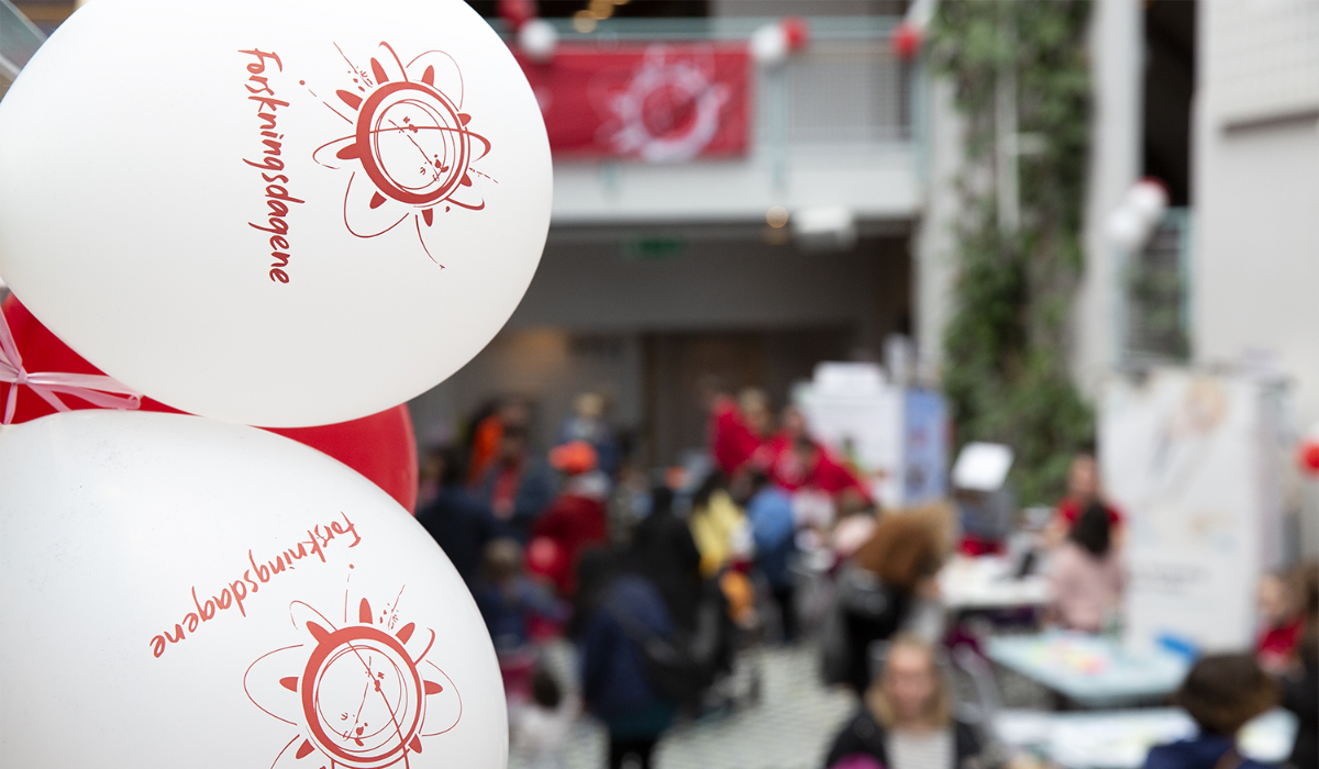 Nærbilde av to hvite ballonger med Forskningsdagene sitt logosymbol i rødt