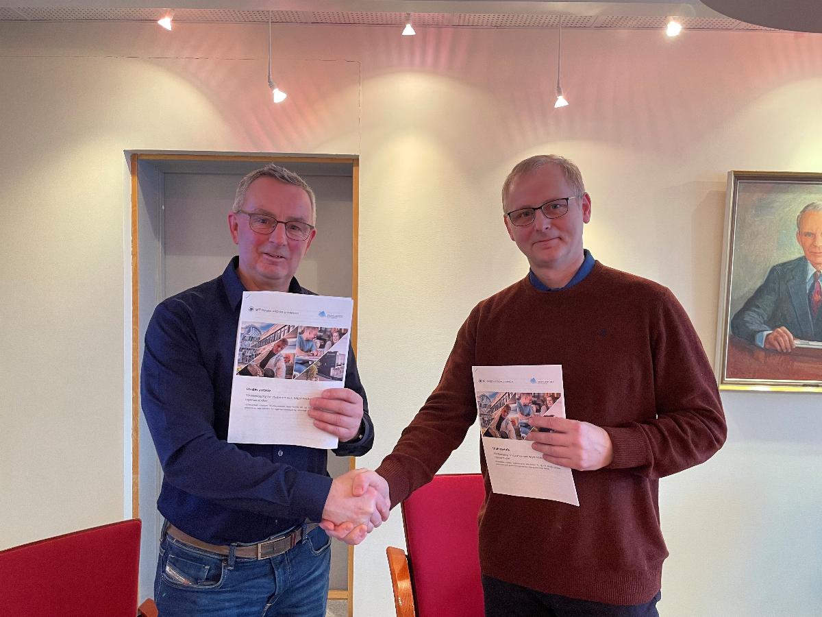 To menn tar hverandre i h&aring;nden etter &aring; ha signert avtale. 