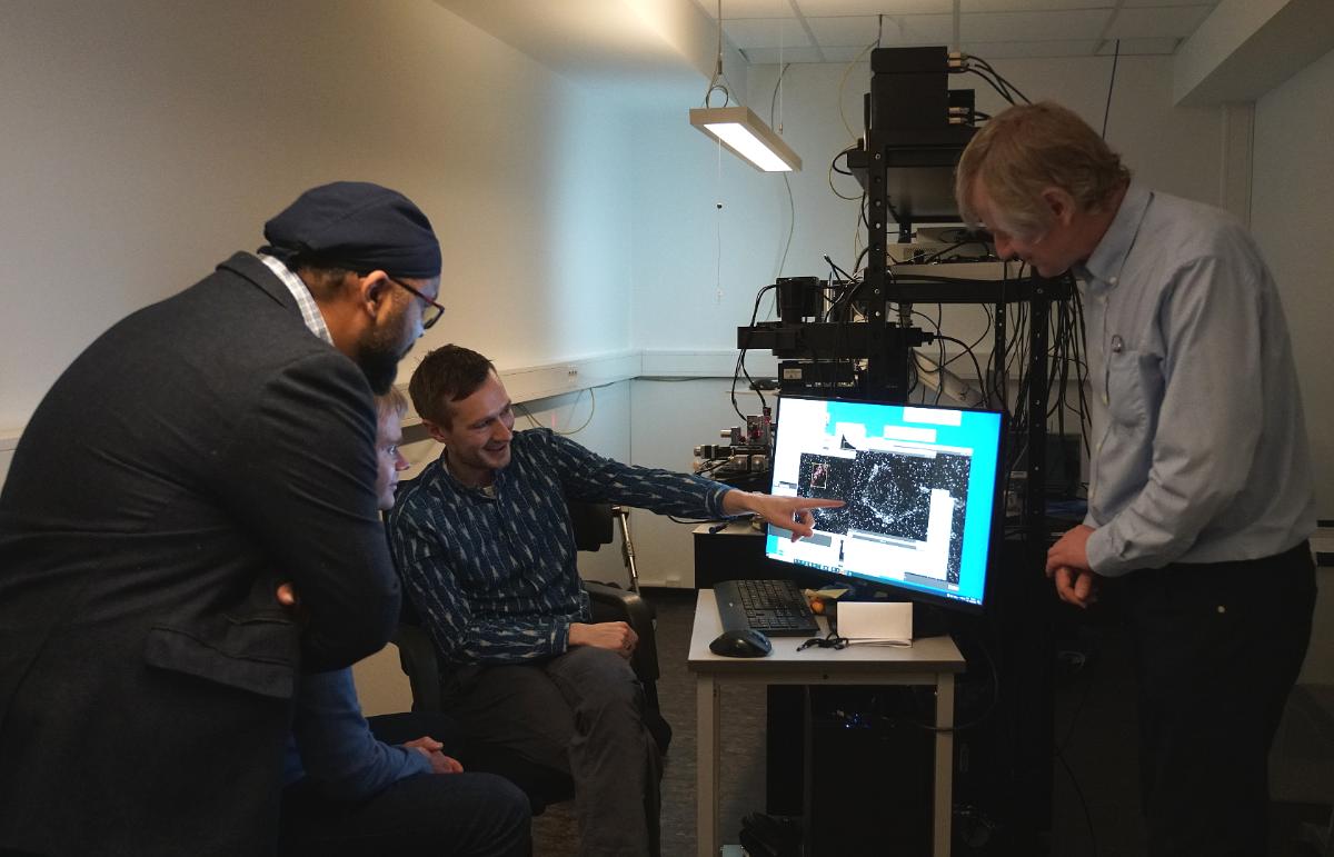 Fire menn ser på ein skjerm i ei lab.