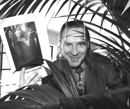 Somby st&aring;r bak ei busk, med doktorgradsavhandlingen sin i h&aring;nd.