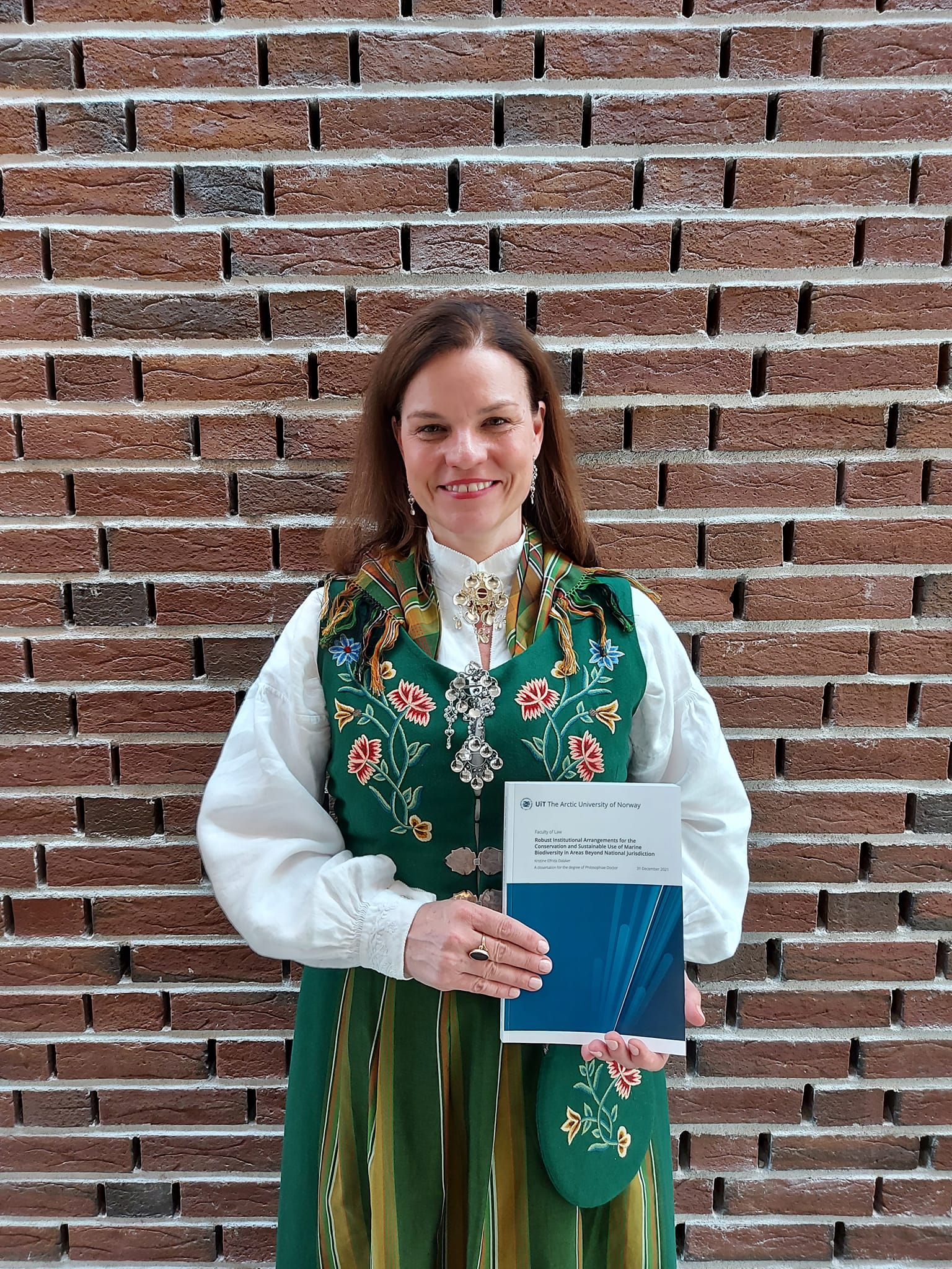 Kristine Elfrida Dalaker poserer med avhandlingen sin i h&aring;nd.