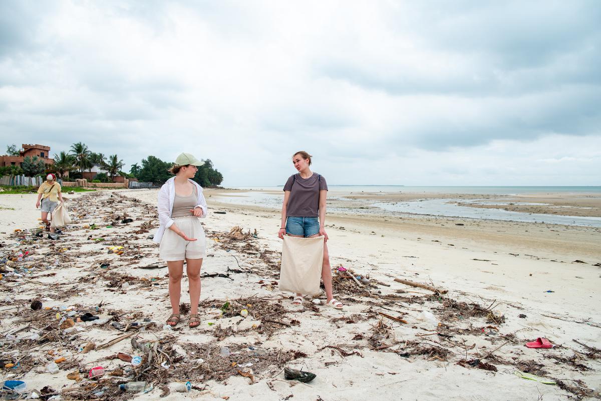 To jenter går på en strand fylt med søppel