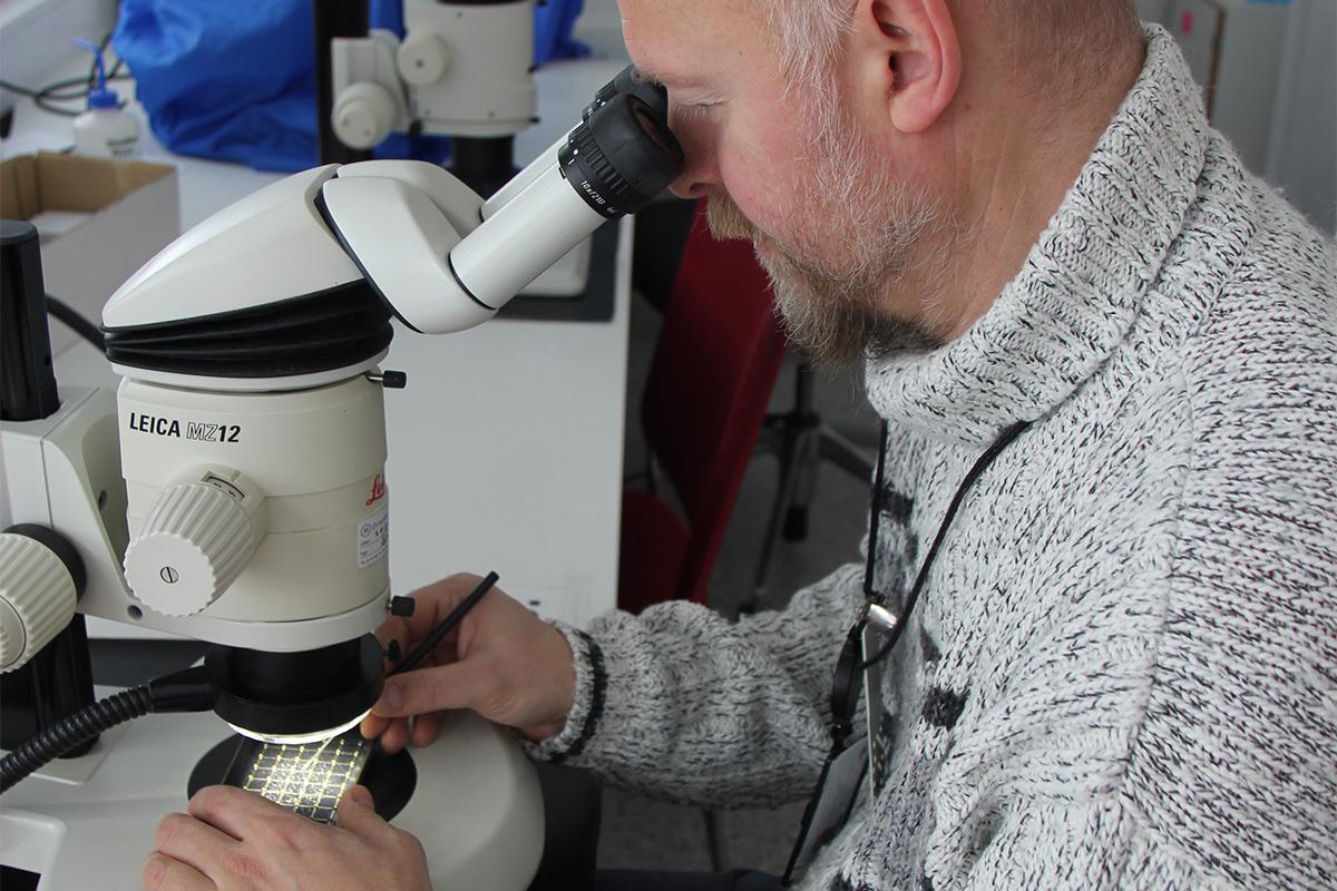 En mann ser i et mikroskop.