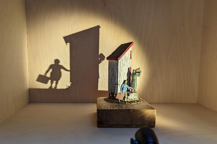 detalj fra en utstilling, enb modell av en jente som flykter fra en soldat som setter fyr på et hus