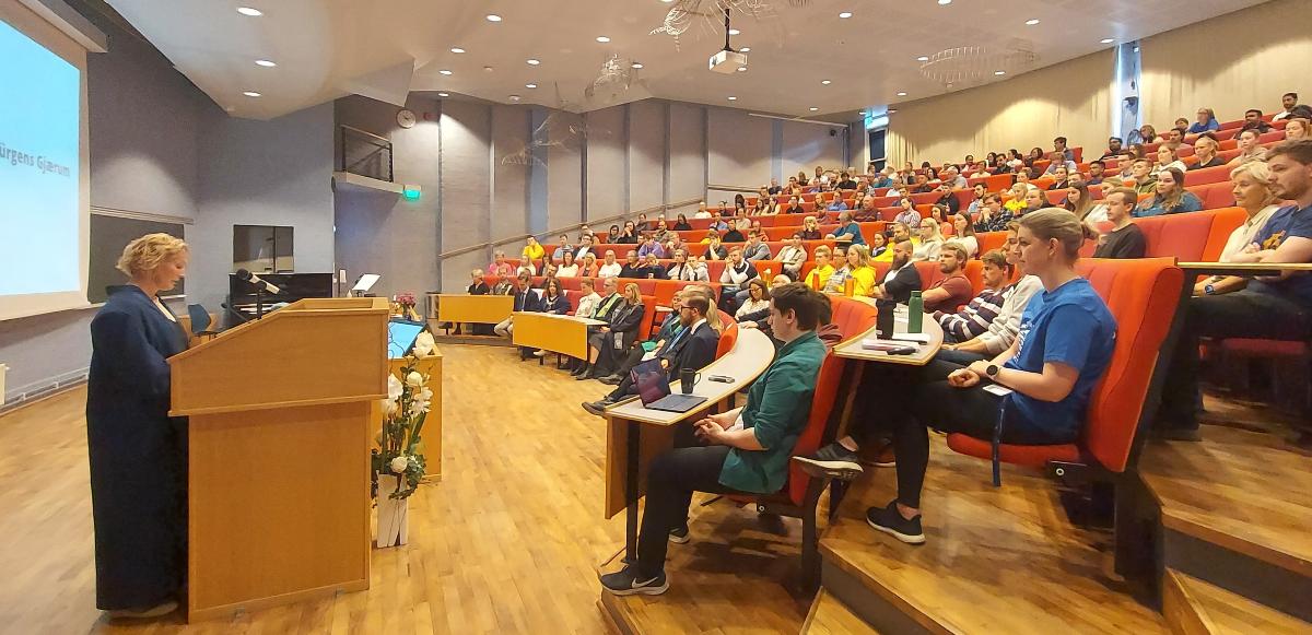 Kvinne taler fullsatt auditorium