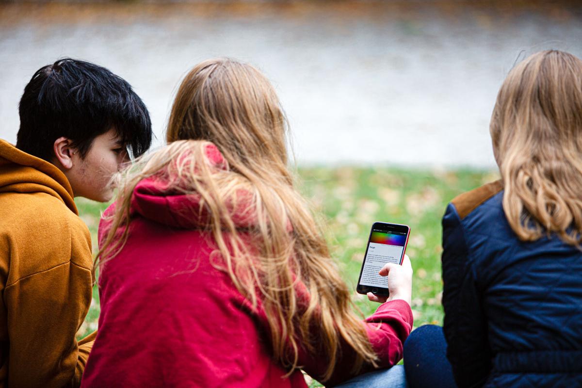 Tre personer leser p&aring; mobiltelefon