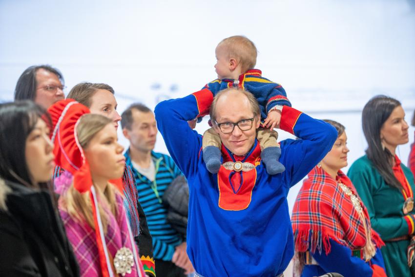 mann med barn p&aring; skuldre i samisk kofte 