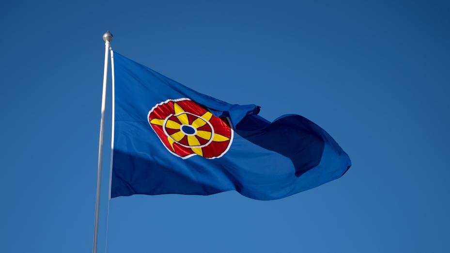 Det kvenske flagget i en flaggstang mot en blå himmel