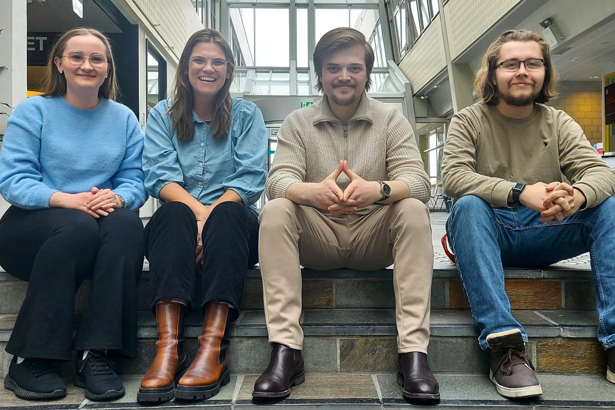 Fire personer sittende i en trapp smiler til fotografen