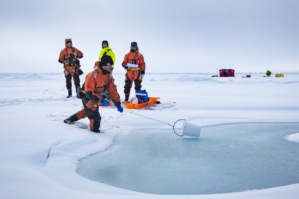 Fire personer stå på isen og gjør undersøkelser. 