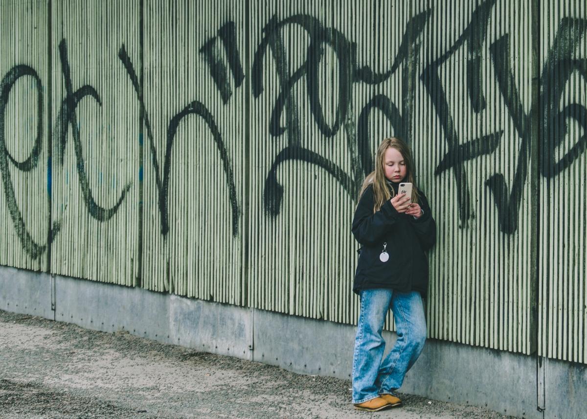 jente som ser på skjerm foran grafittivegg