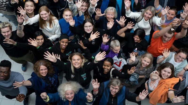 Mange glade folk jublar og rekke hendene opp mot kamera