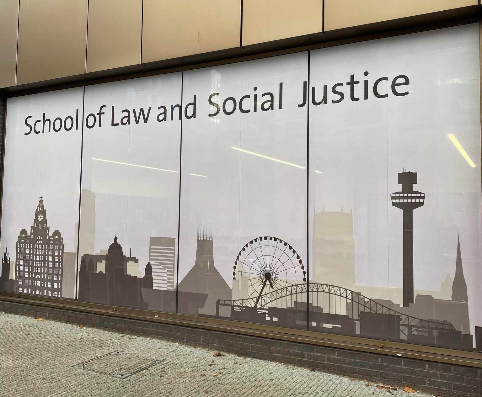 Bilde av en vegg med en plakat for Lawschoolen og School of Social Justice.