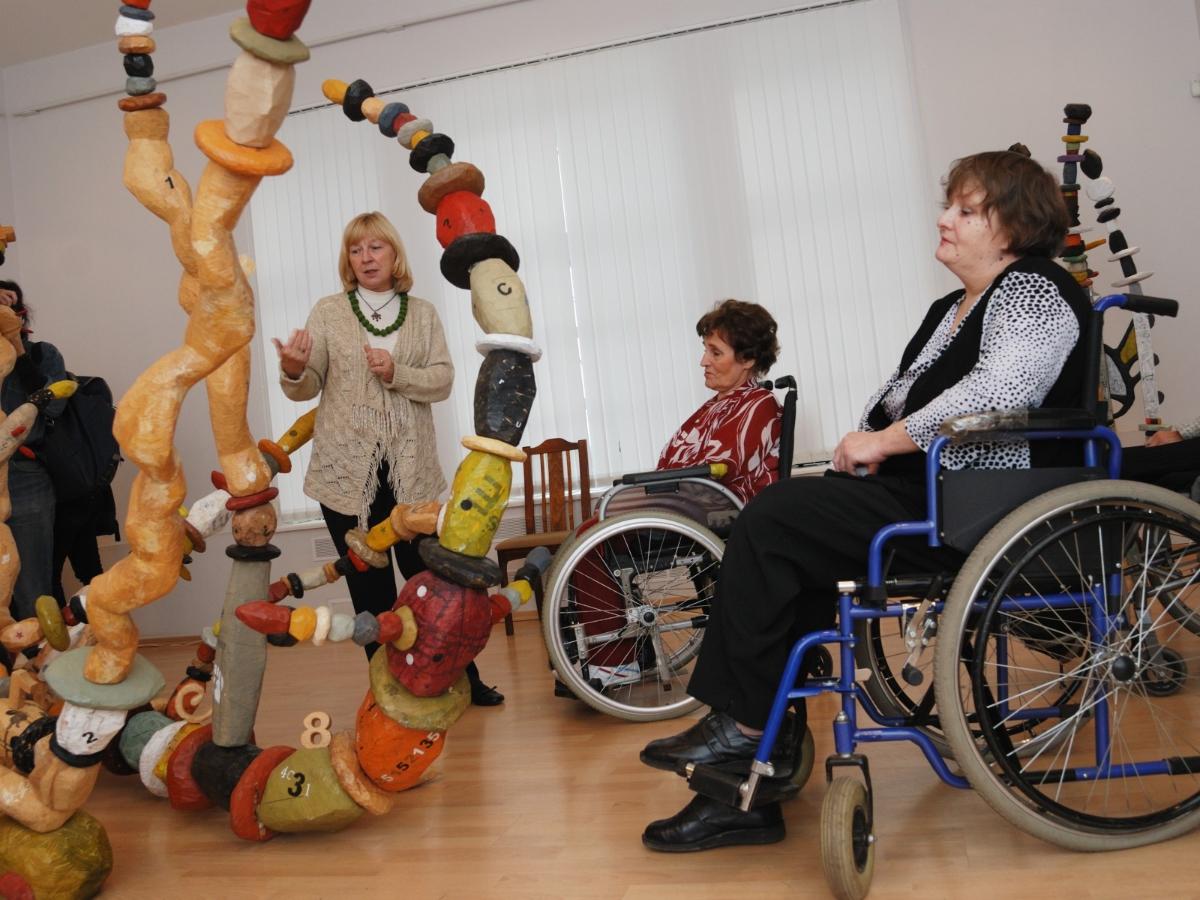 Personer i rullestol ser på kunst.