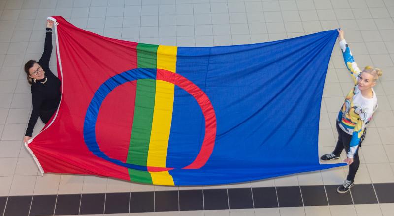 To kvinner holder fram det samiske flagget mellom seg. 