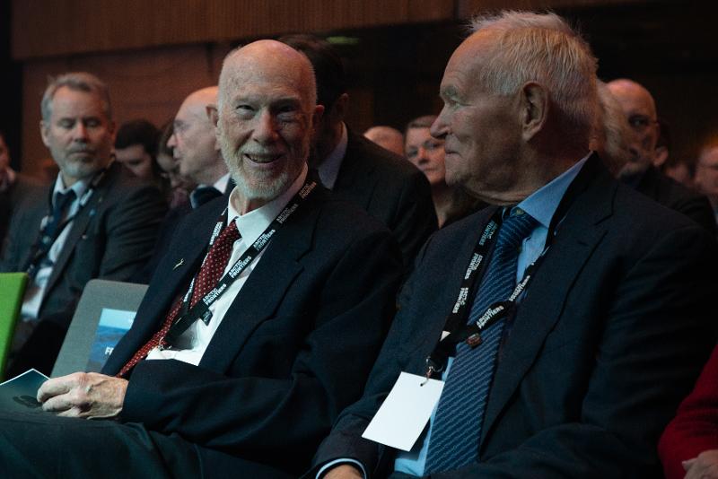 To eldre menn sit og snakkar saman i ein konferansesal