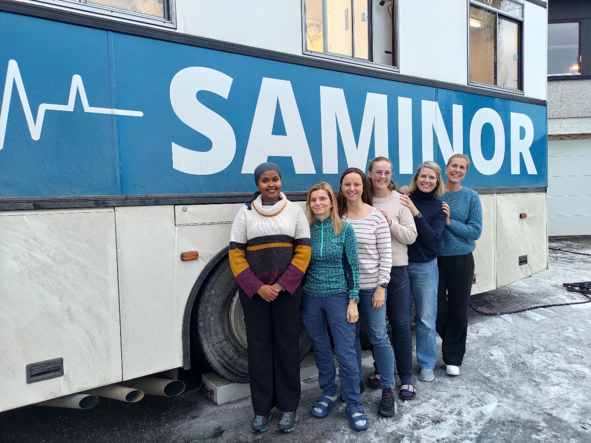 Seks kvinner posere foran en buss. Det står SAMINOR på bussen.