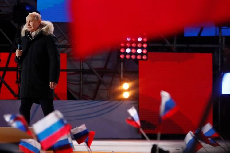 Vladimir Putin stor på en scene med rød bakgrunn