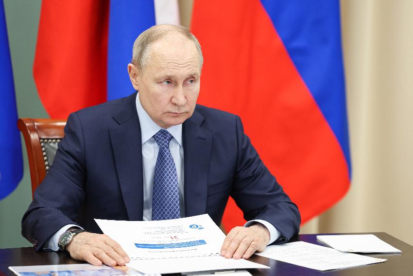 Vladimir Putin stor på en scene med rød bakgrunn