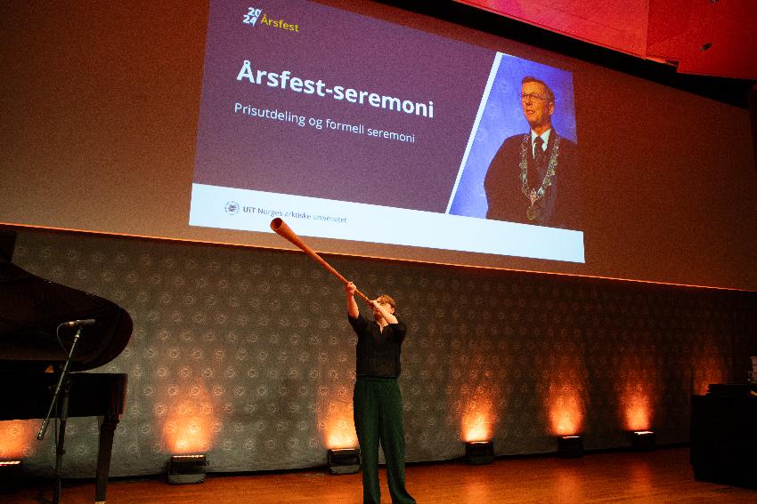Fløytespiller på podium før prisutdeling på et universitet. 