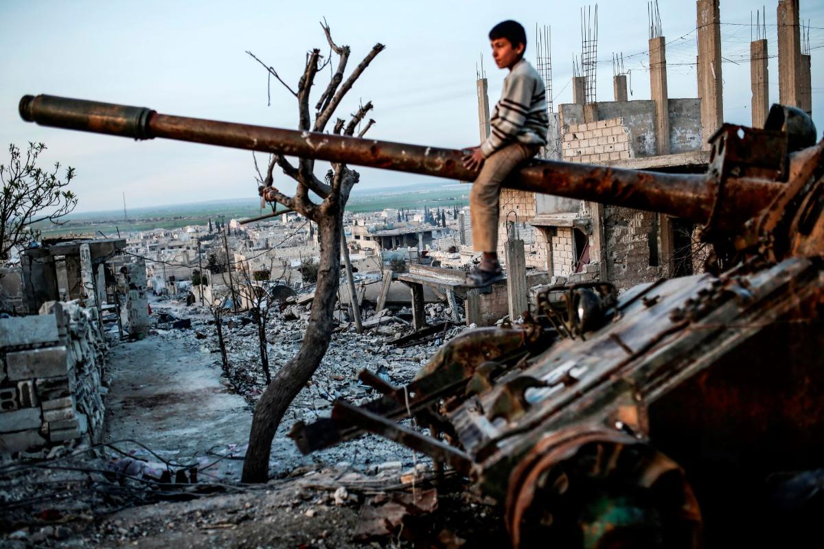 gutt i syria sitter oppå tanks i ruiner