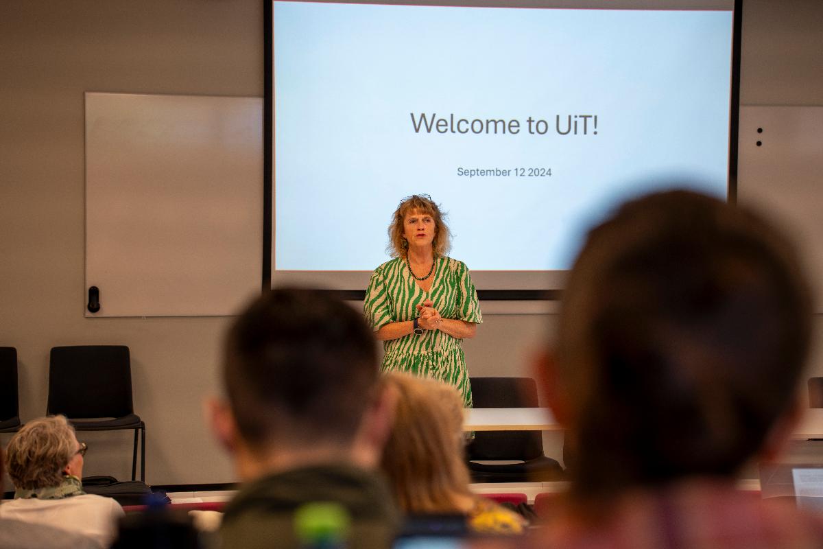 Kvinne står foran en tavle der det står Welcome to UiT!