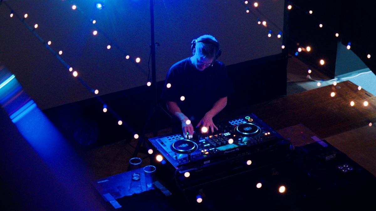 mannlig DJ snurrer plater, sett ovenfra gjennom stemningsfulle lyslenker