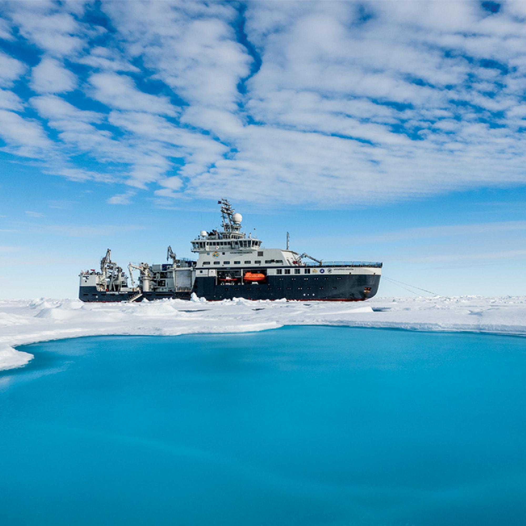 A boat in the ice with blue water in front