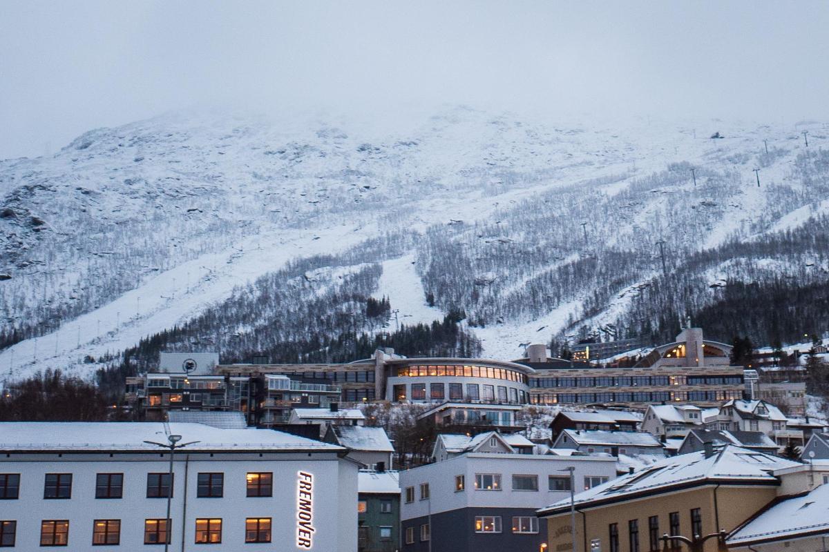 Biler som kjører i bysentrum, uit narvik midt i bildet foran et fjell med en skibakke