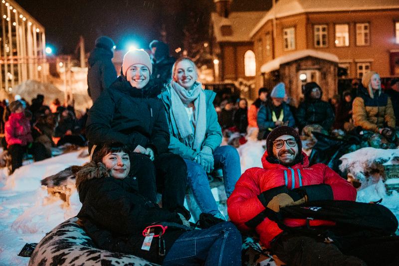 Vinterkledde deltakere på utekino i arktisk by. 