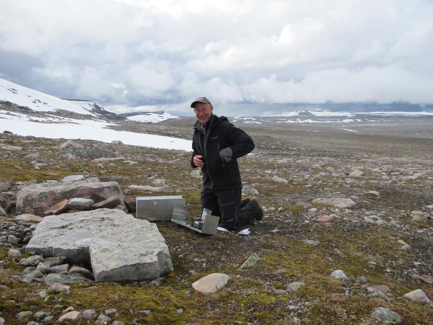 En mann sitter på bakken med et forskningsinstrument.