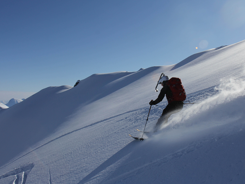 Person står på ski i et snøkledd fjell