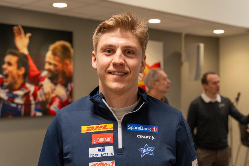 mann som smiler og har jakke med sponsor-logoer