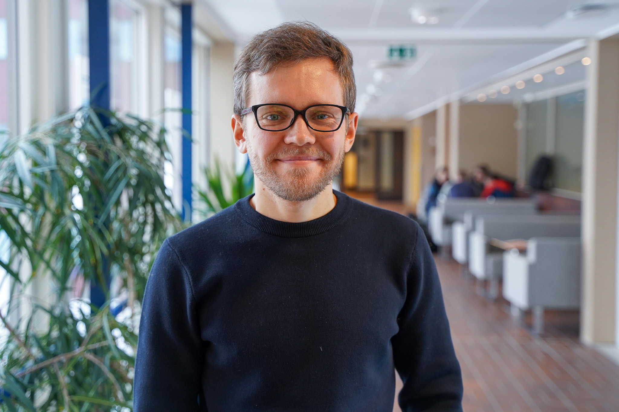 En mann står og smiler foran et kamera