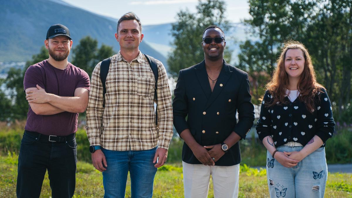 Four people standing in a line, faces forward, in nature