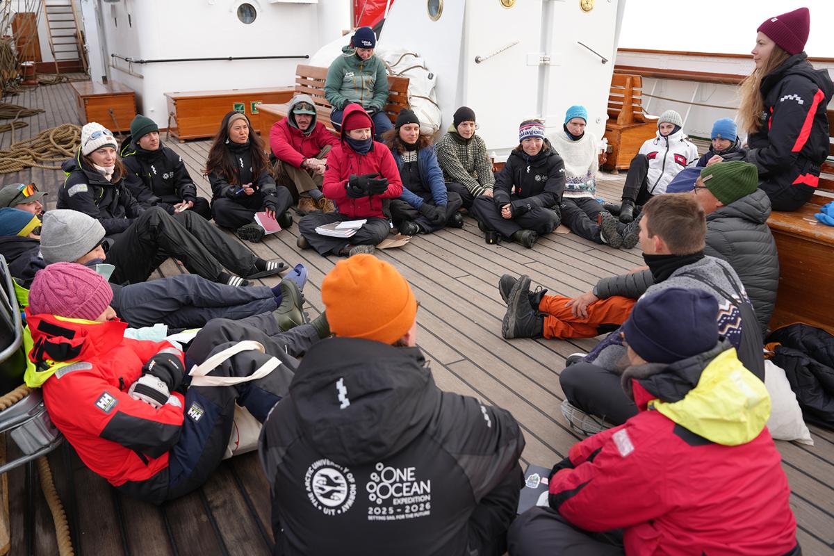 Mange personer sitter på dekket av en båt.