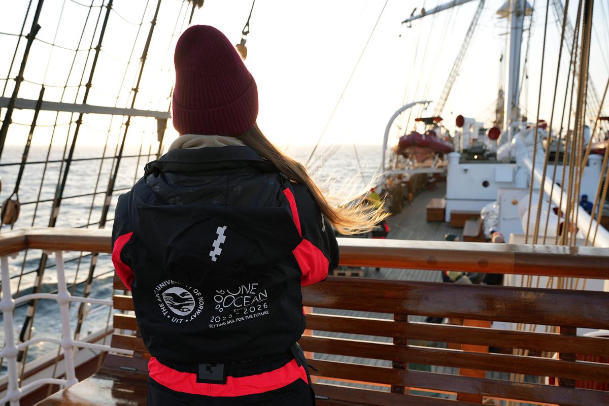 En person står på dekk, fotografert bakfra