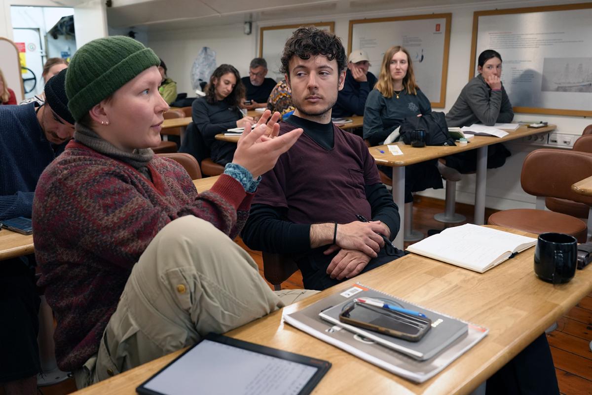 A person talking with others in the background.