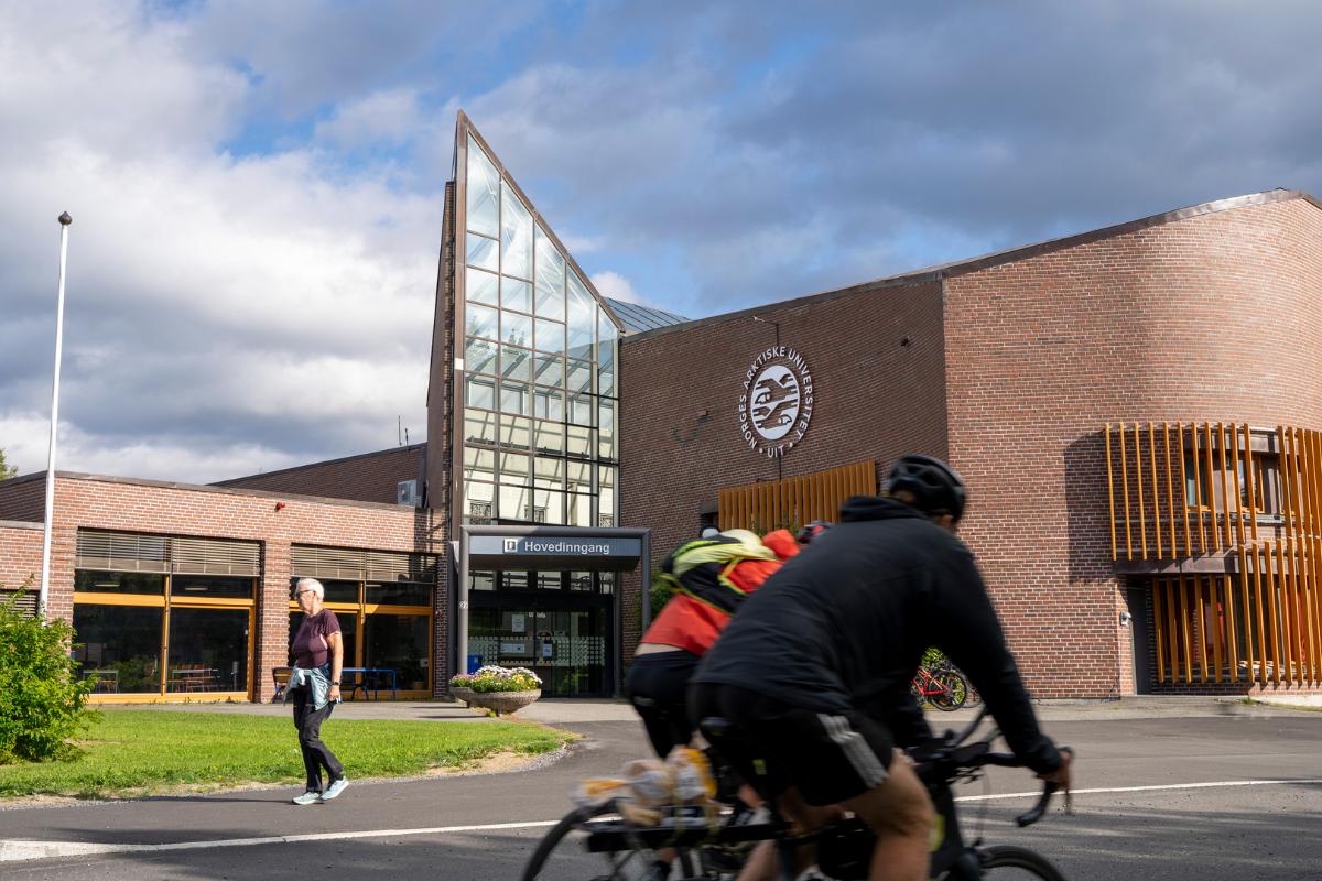 ein brun bygning, med syklistar og gåande foran