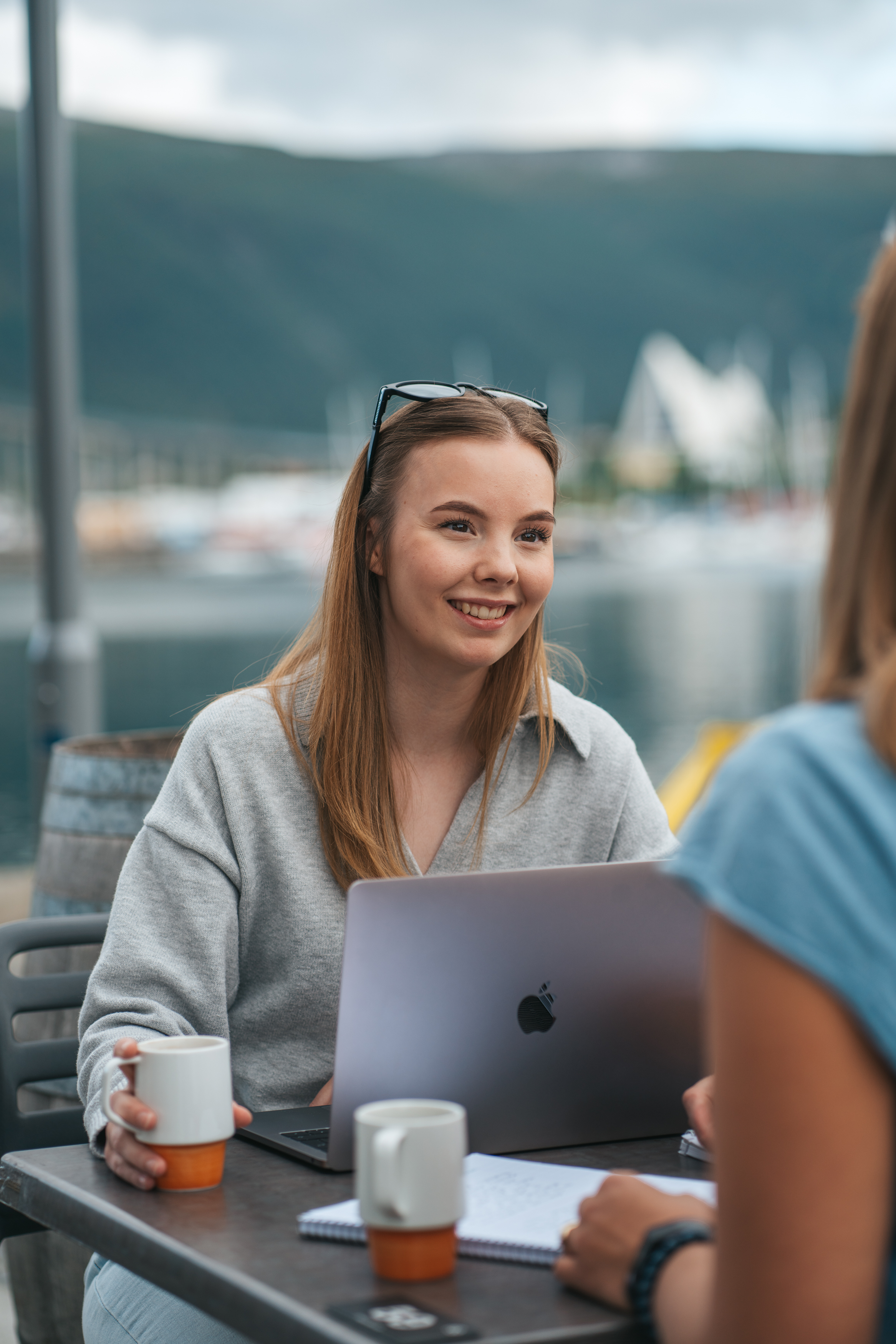 Smilende ung kvinne foran pc utend&oslash;rs