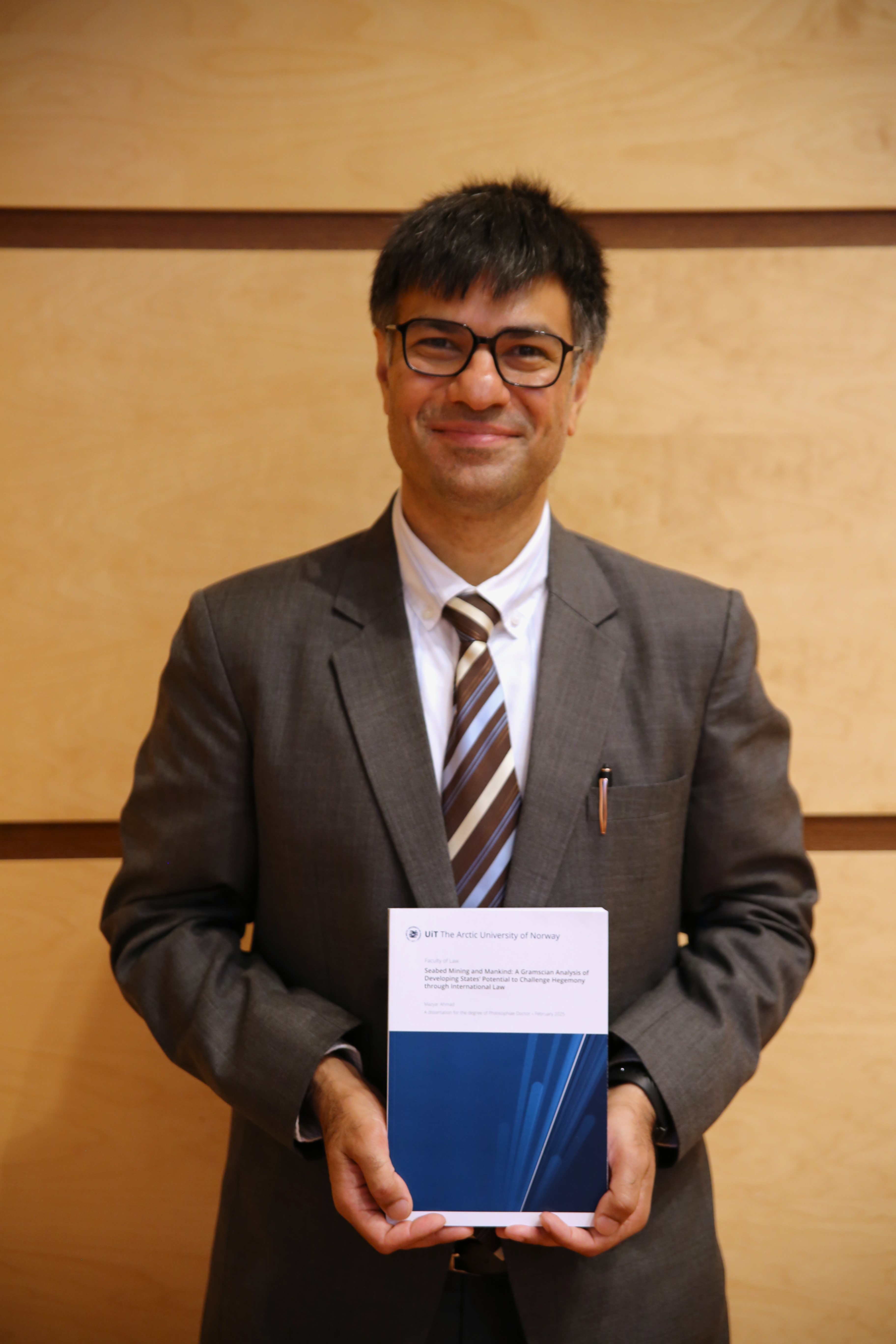 PhD Ahmad poserer med sin avhandling.
